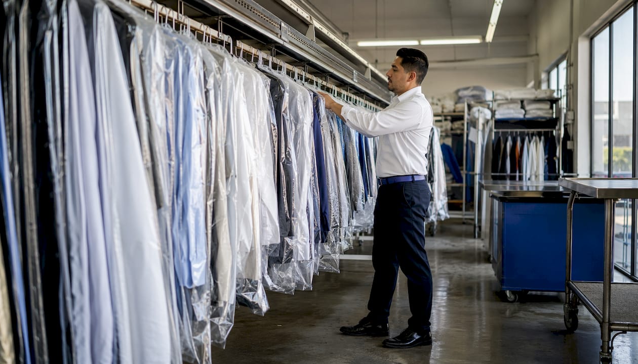 Employee adjusting dry cleaning conveyor rack