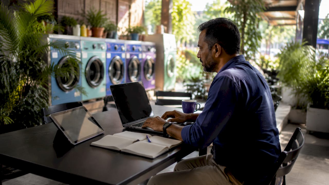 Laundromat owner managing machines remotely on laptop