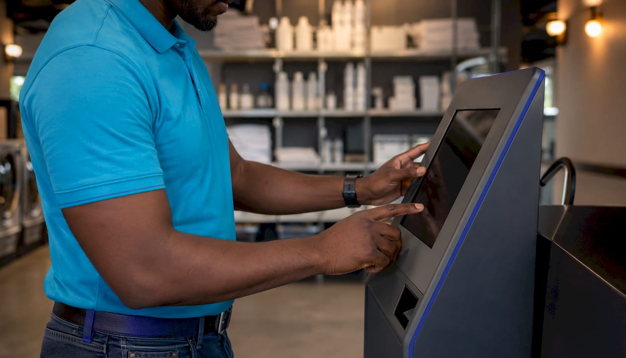Hands maintaining laundromat payment kiosk