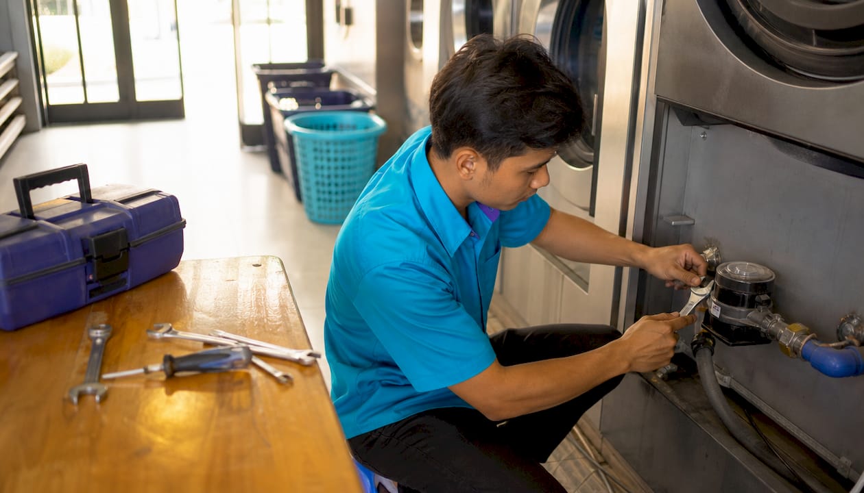 Technician installing water sub-meter on washing machine