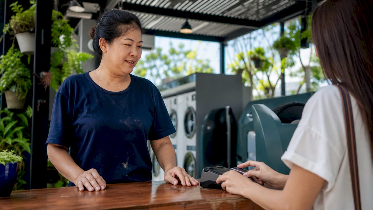 Laundromat attendant assisting digital payment