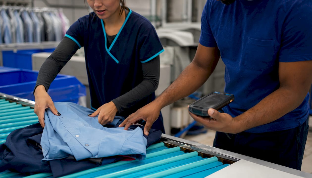 Two workers using mobile POS device in sorting room